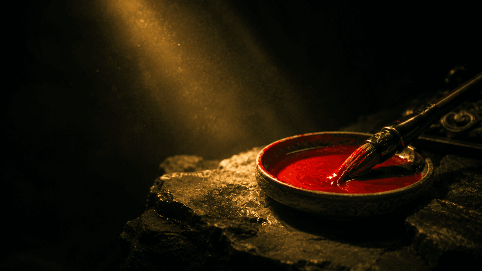 A dish of cinnabar ink with a calligraphy brush on dark stone